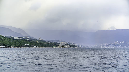 Scenic view of sea by buildings against sky