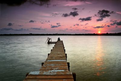 Pier over lake against sky during sunset