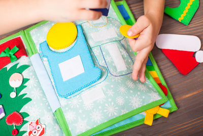 High angle view of girl holding multi colored art on table