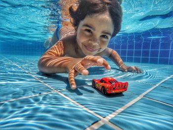 Portrait of cute boy playing with toy car in swimming pool