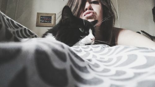 Portrait of young woman puckering with cat on bed at home