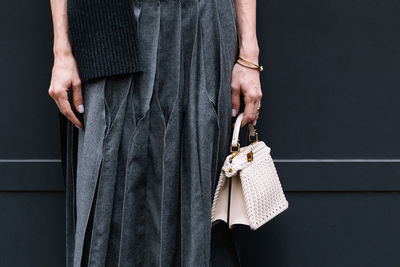 Midsection of woman standing against wall