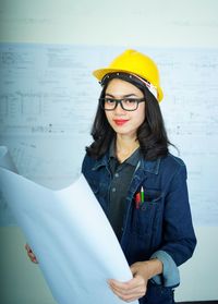 Mid adult woman wearing hat standing against wall
