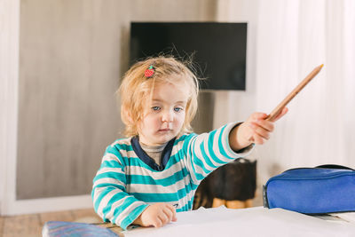 Girl with pencil studying on table at home