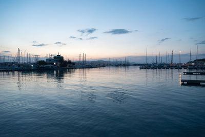 Sailboats moored on sea against sky during sunset