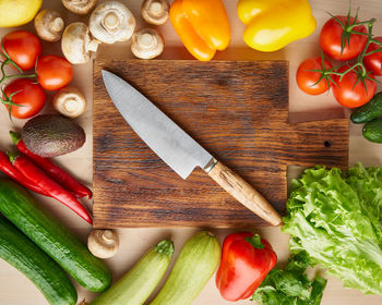 Vegetables around wooden cutting board with knife on kitchen table. top view. food ingredient 