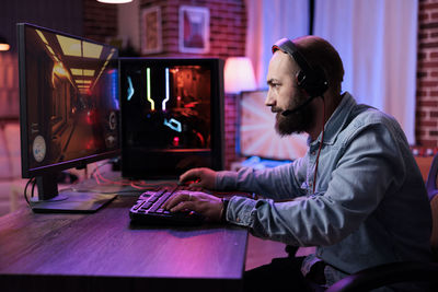 Rear view of man using laptop at office