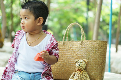 Cute baby boy looking away while eating fruit outdoor