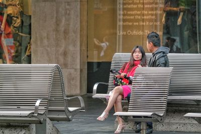 Portrait of a smiling young woman sitting on staircase in city