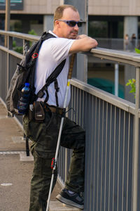 Man holding camera while standing against built structure