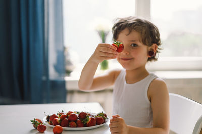 Cute beautiful little boy eating fresh cherry and strawberry.