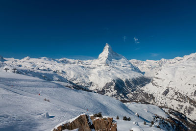 Scenic view of snowcapped mountains against clear blue sky