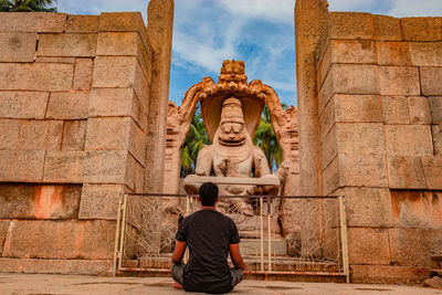 Rear view of man against statue in temple