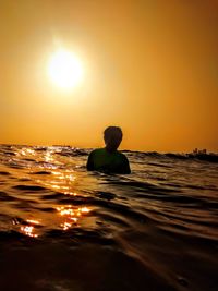 Teenage boy in sea during sunset