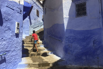 Rear view of woman walking by buildings