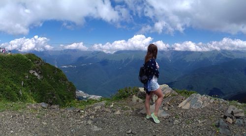 Young woman standing on mountain against sky