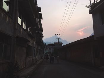 People on street in city against sky during sunset