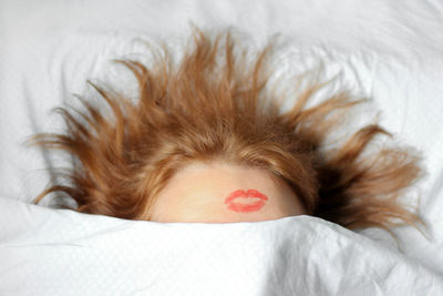 Woman with lipstick mark on head sleeping on bed