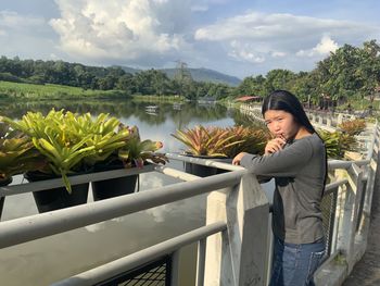 Woman standing by railing against lake