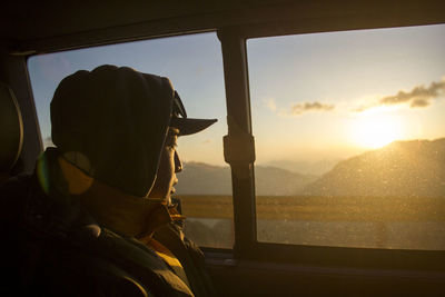 Rear view of woman standing against sky during sunset