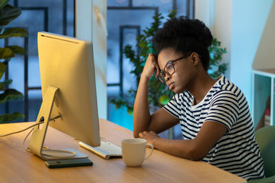 Tired remote employee at home office, unmotivated exhausted african student girl studying online