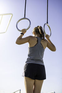 Rear view of woman exercising against sky