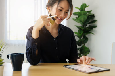 Young woman using phone on table