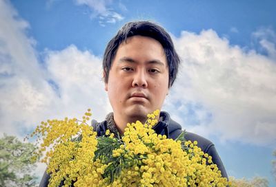 Portrait of man against plants against cloudy sky