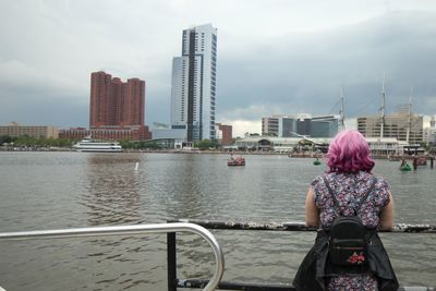 Rear view of woman standing by river in city