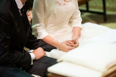 Midsection of couple holding hands during wedding ceremony