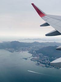 Aerial view of airplane flying over cityscape against sky