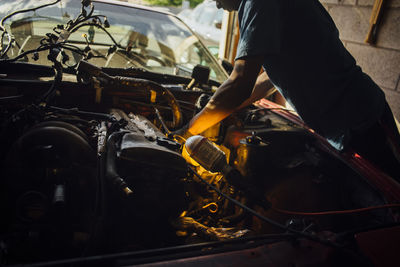 Midsection of mechanic repairing car