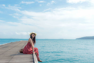 Full length of young woman in sea against sky
