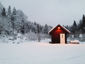 Snow covered field by trees against sky during winter