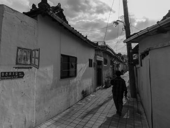 Man walking on road along buildings