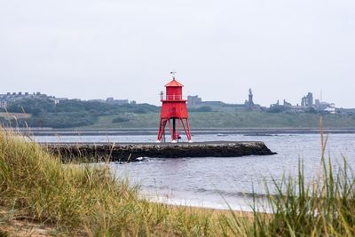 Lighthouse by lake against clear sky