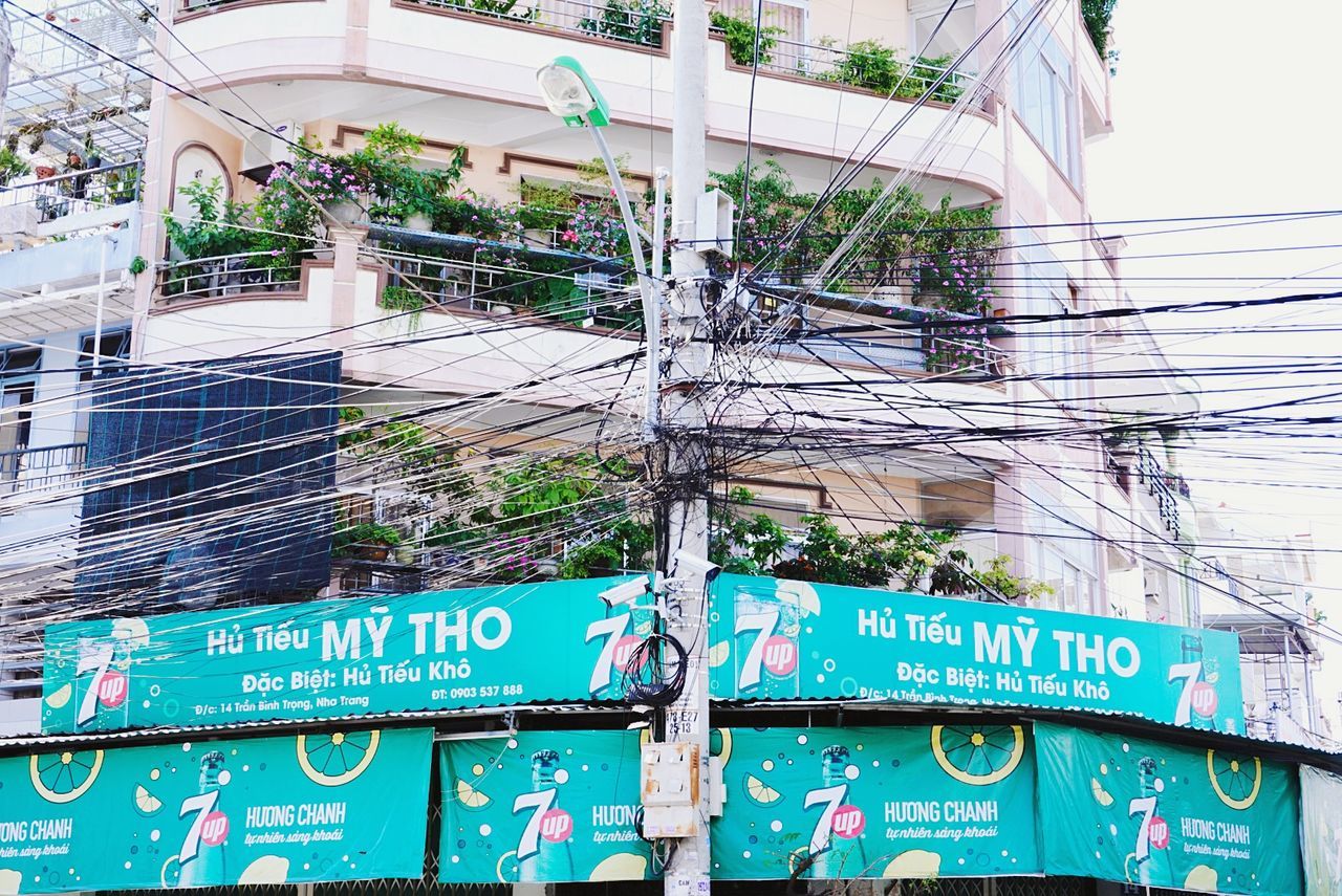 built structure, architecture, building exterior, communication, electricity, text, day, low angle view, cable, no people, connection, building, power line, technology, outdoors, power supply, western script, nature, tree, plant, complexity, telephone line