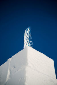 Low angle view of snow covered mountain against blue sky