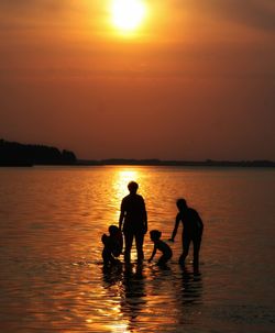 Silhouette children on beach against sky during sunset