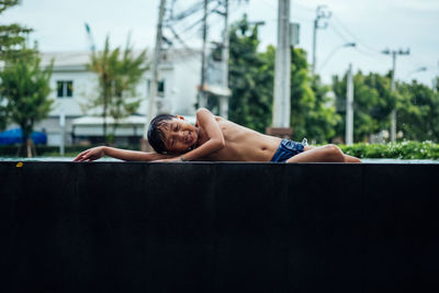 Shirtless boy lying by swimming pool