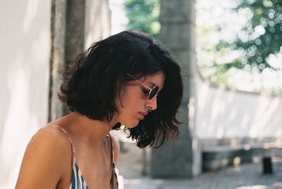 Side view of thoughtful young woman wearing sunglasses