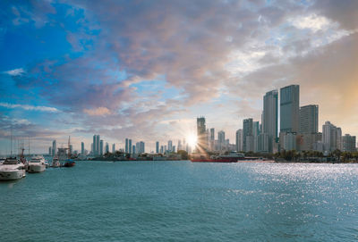 Sea by city buildings against sky