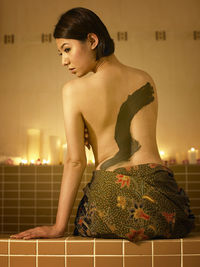Rear view of woman with mud on back sitting at spa