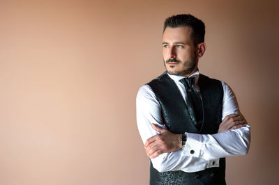 Portrait of young man standing against gray background