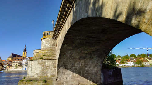 Arch bridge over river amidst buildings against sky