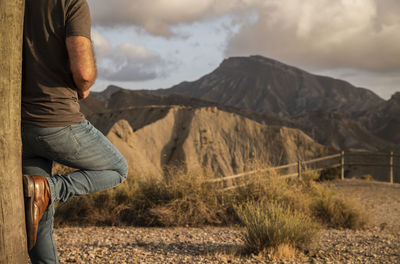 Low section of man relaxing on land against sky, in tabernas desert, almeria, spain