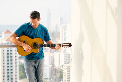 Man playing guitar standing at home