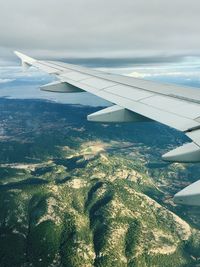 Cropped image of airplane flying over landscape against sky