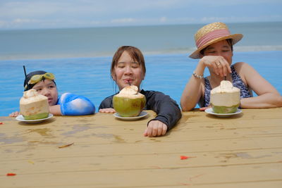 Portrait of mother and daughters having coconut drink while swimming in sea
