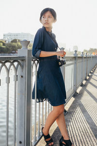 Portrait of woman standing on railing against bridge